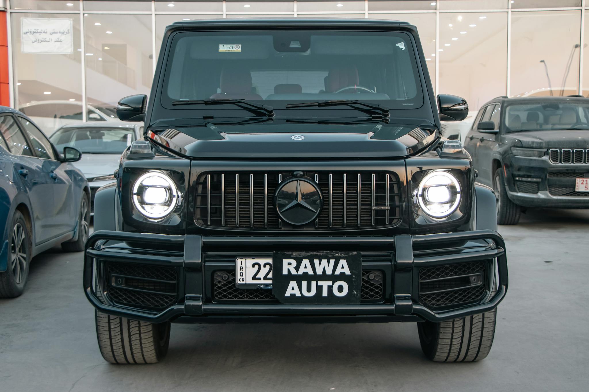 Front view of a sleek black Mercedes G-Class SUV parked in a modern showroom.